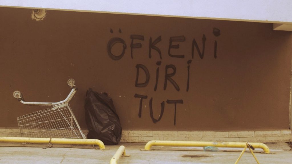 a shopping cart leaning against a wall with graffiti on it